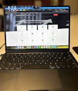 A laptop displaying a website with a search bar at the top and several categorized icons for different services. The laptop is positioned on a light-colored desk in an indoor setting, with the focus on the screen contents and some blurred background elements.